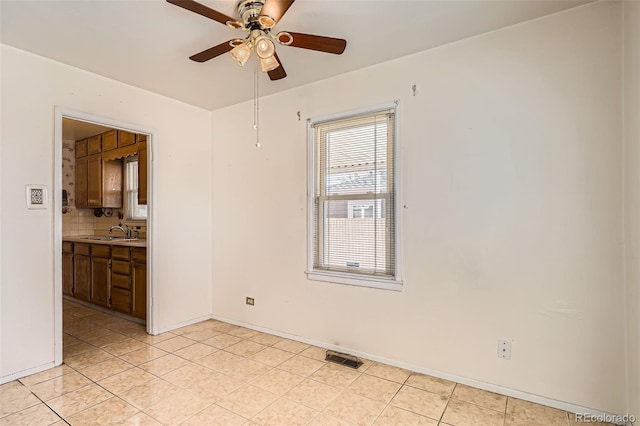 unfurnished room with visible vents, a sink, light tile patterned floors, baseboards, and ceiling fan