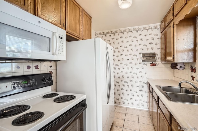 kitchen featuring white microwave, wallpapered walls, a sink, electric range oven, and brown cabinets