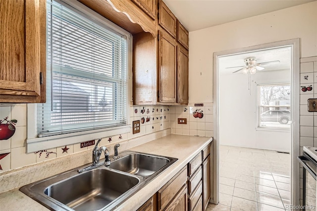 kitchen featuring electric range, a sink, light countertops, brown cabinets, and backsplash