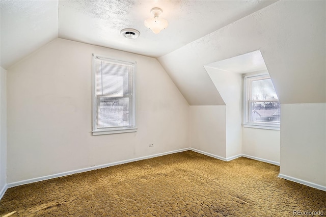 additional living space with vaulted ceiling, carpet, baseboards, and a textured ceiling