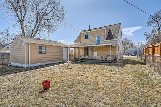 back of property featuring a porch, an outdoor structure, a yard, and fence