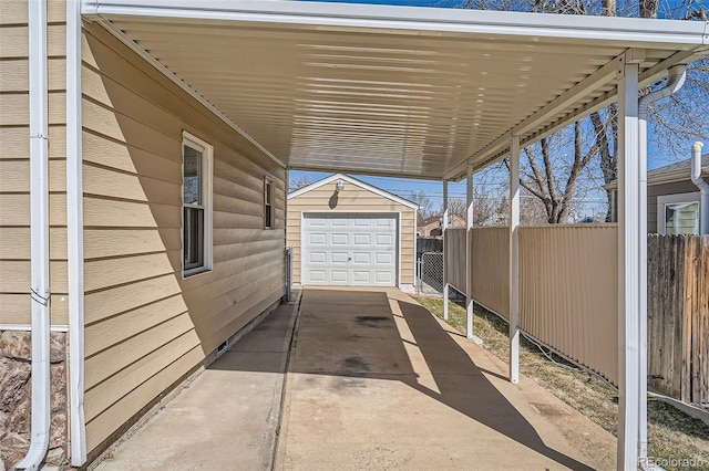 view of patio / terrace featuring an outbuilding, driveway, a detached garage, fence, and a carport