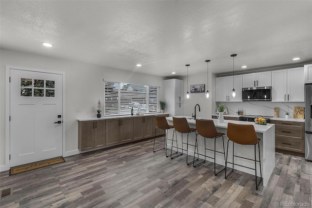 kitchen featuring light countertops, a textured ceiling, stainless steel appliances, and wood finished floors