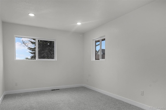 carpeted empty room featuring baseboards, recessed lighting, and visible vents