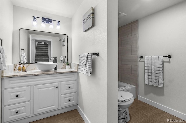 full bath with toilet, baseboards, wood finished floors, and vanity