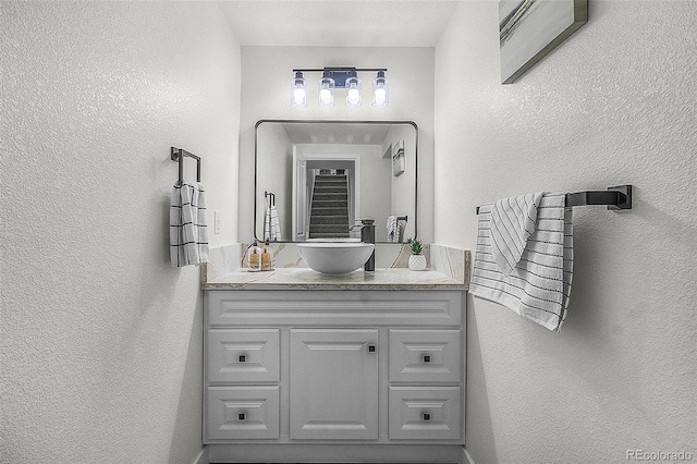 bathroom with a textured wall and vanity