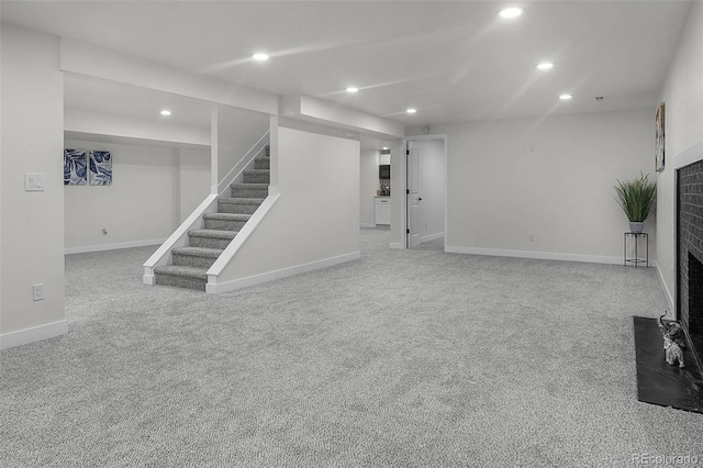 unfurnished living room featuring recessed lighting, carpet, stairs, and a brick fireplace