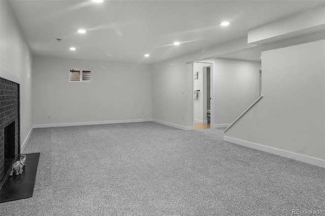 finished basement with recessed lighting, light carpet, and a fireplace