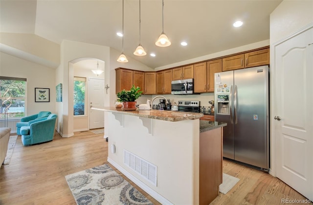 418 Hilltop Cir, Colorado Springs, CO 80905 - kitchen with appliances with stainless steel finishes, vaulted ceiling, brown cabinetry, dark stone counters, and light wood-style floors