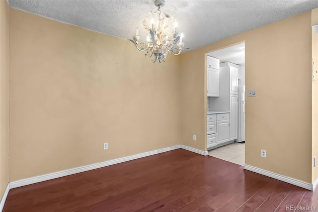 2 Adams St Unit 1507, Denver, CO 80206 - unfurnished room featuring light wood-style flooring, a chandelier, baseboards, and a textured ceiling