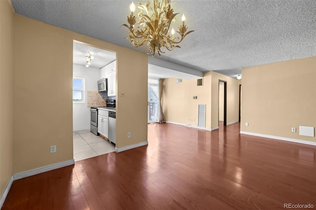 2 Adams St Unit 1507, Denver, CO 80206 - unfurnished living room featuring a chandelier, a textured ceiling, light wood-style floors, and baseboards