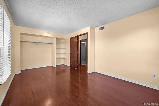 2 Adams St Unit 1507, Denver, CO 80206 - unfurnished bedroom with a textured ceiling, baseboards, a closet, and wood finished floors