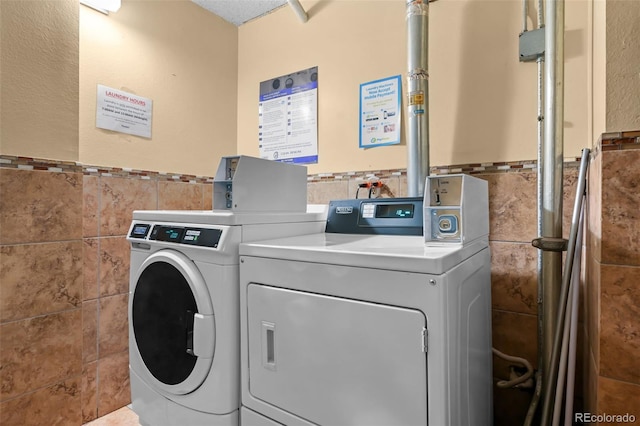 2 Adams St Unit 1507, Denver, CO 80206 - shared laundry featuring tile walls, washing machine and dryer, and a wainscoted wall