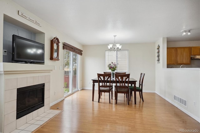 dining area with light hardwood / wood-style floors, a chandelier, and a fireplace