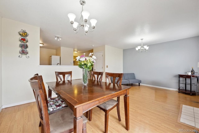 dining area with a notable chandelier and light hardwood / wood-style flooring