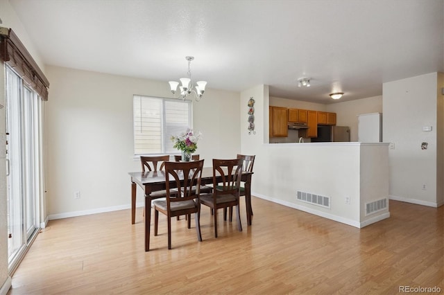 dining room with light hardwood / wood-style flooring and an inviting chandelier