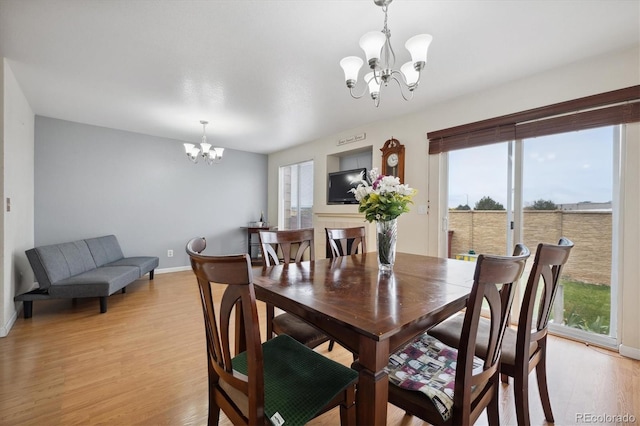 dining room with light wood-type flooring and an inviting chandelier