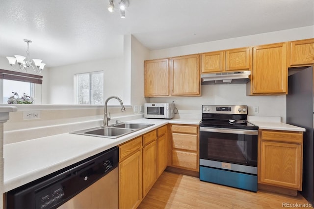 kitchen with a notable chandelier, pendant lighting, sink, light hardwood / wood-style flooring, and appliances with stainless steel finishes