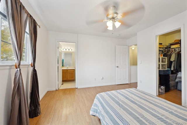 bedroom with ceiling fan, light hardwood / wood-style flooring, connected bathroom, a walk in closet, and a closet