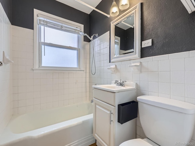 full bathroom featuring tile walls, tiled shower / bath, vanity, and toilet