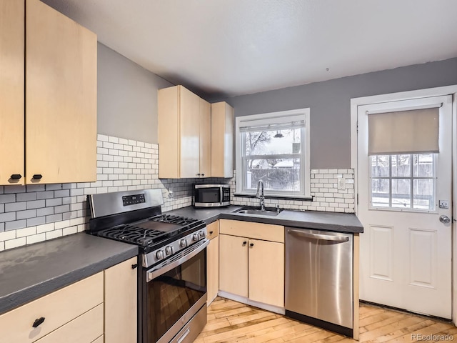 kitchen featuring appliances with stainless steel finishes, light hardwood / wood-style floors, sink, and decorative backsplash