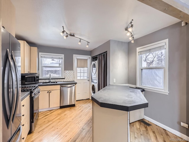 kitchen with stacked washer / drying machine, plenty of natural light, stainless steel appliances, and a center island