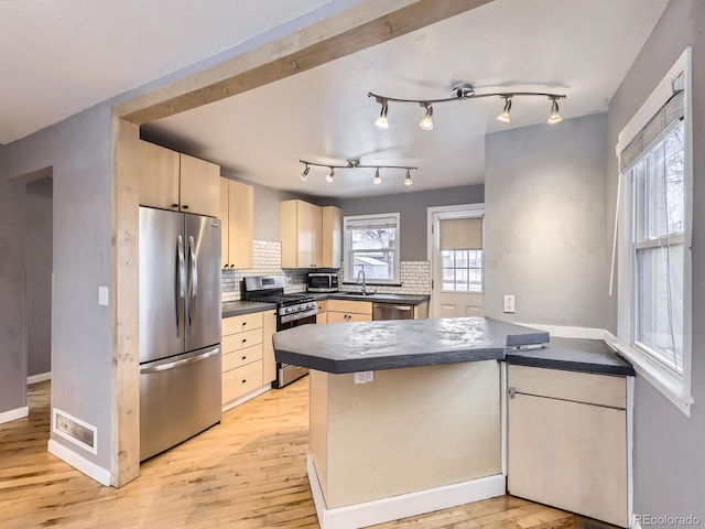 kitchen with light brown cabinetry, sink, kitchen peninsula, stainless steel appliances, and light wood-type flooring