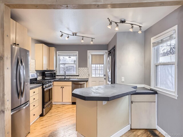 kitchen featuring sink, backsplash, kitchen peninsula, stainless steel appliances, and light hardwood / wood-style flooring