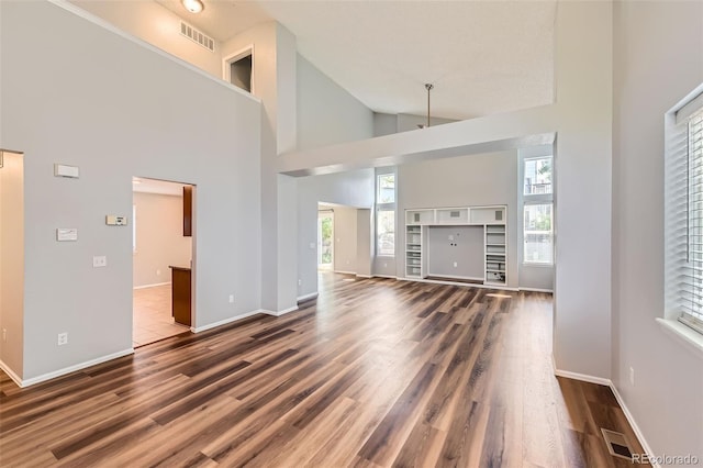 8750 Redwing Ave, Littleton, CO 80126 - unfurnished living room with healthy amount of natural light, high vaulted ceiling, wood finished floors, and baseboards