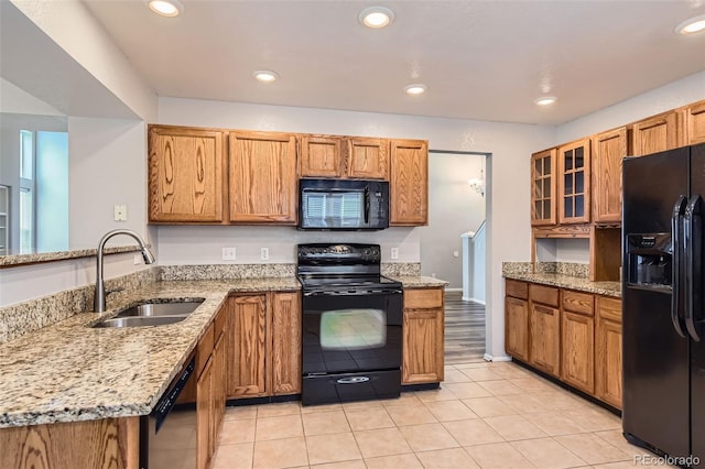 8750 Redwing Ave, Littleton, CO 80126 - kitchen with black appliances, a sink, a peninsula, glass insert cabinets, and brown cabinets
