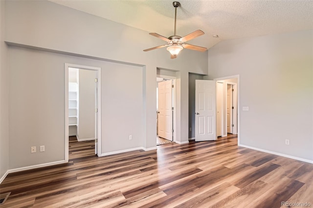 8750 Redwing Ave, Littleton, CO 80126 - unfurnished bedroom featuring wood finished floors, a walk in closet, baseboards, a textured ceiling, and high vaulted ceiling