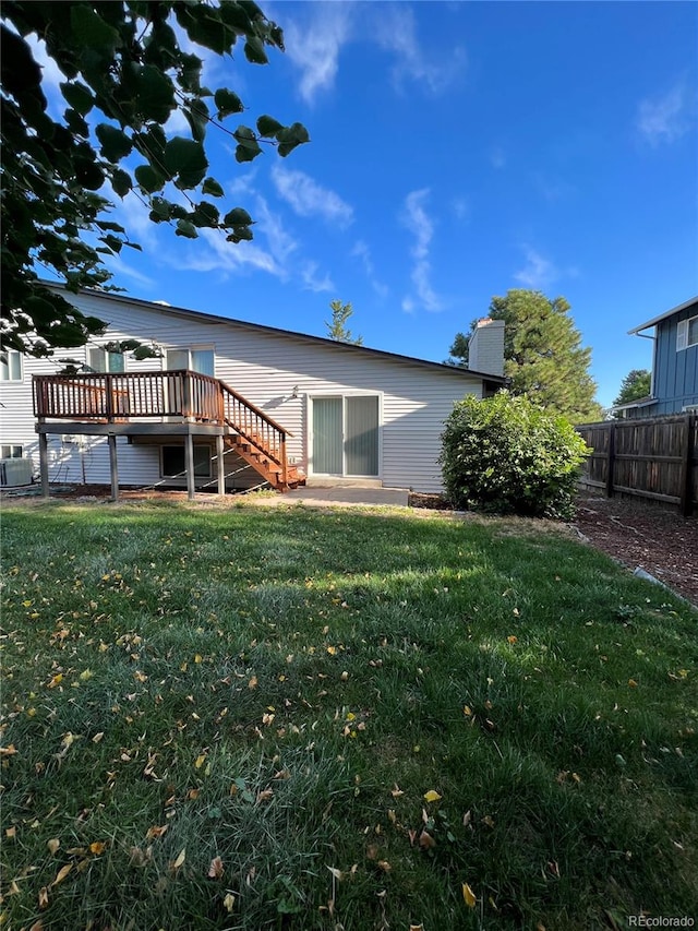 back of house featuring a lawn and a wooden deck