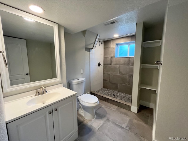 15908 E Flora Pl, Aurora, CO 80013 - bathroom featuring a textured ceiling, toilet, vanity, and a tile shower