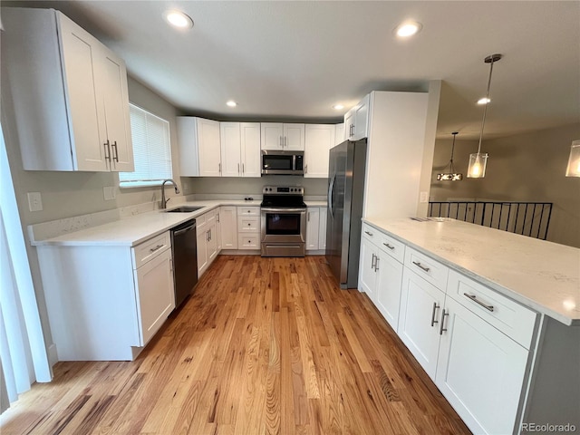 15908 E Flora Pl, Aurora, CO 80013 - kitchen with appliances with stainless steel finishes, a sink, light wood finished floors, a peninsula, and white cabinetry