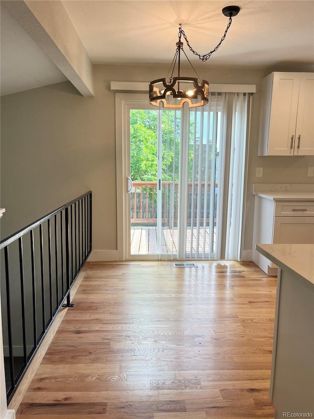 15908 E Flora Pl, Aurora, CO 80013 - unfurnished dining area with light wood-style floors, a chandelier, and baseboards