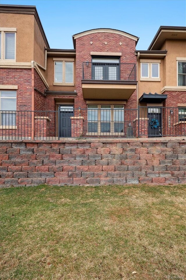 exterior space with stucco siding, brick siding, and a front lawn