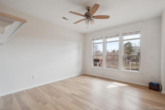 spare room with baseboards, a ceiling fan, visible vents, and light wood-style floors