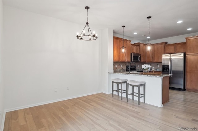 kitchen featuring stainless steel appliances, a peninsula, decorative backsplash, and light wood-style floors