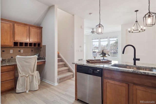 kitchen featuring stainless steel dishwasher, a sink, brown cabinetry, light wood-type flooring, and backsplash