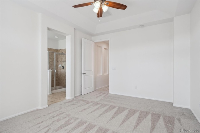 unfurnished bedroom with a raised ceiling, connected bathroom, carpet floors, baseboards, and ceiling fan