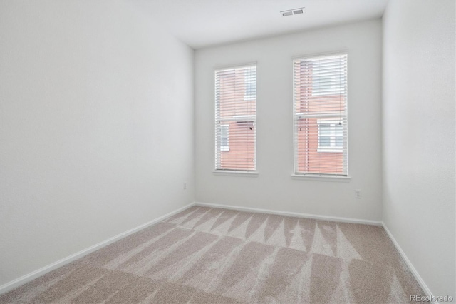 spare room with light carpet, visible vents, and baseboards