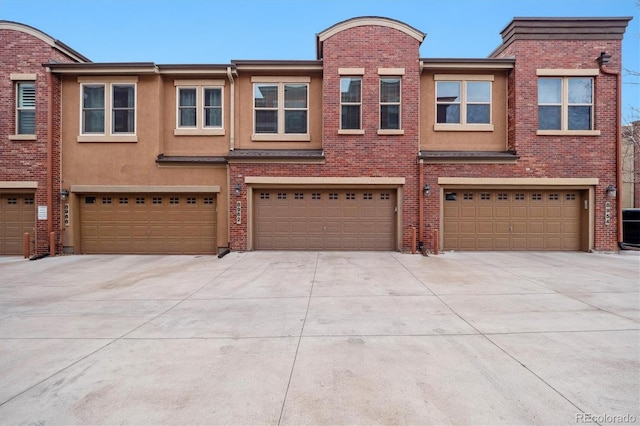 view of property with brick siding, driveway, and a garage