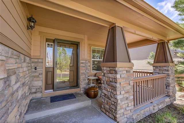doorway to property featuring a porch and stone siding