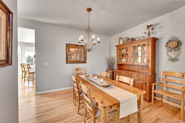dining area with baseboards, an inviting chandelier, and light wood-type flooring
