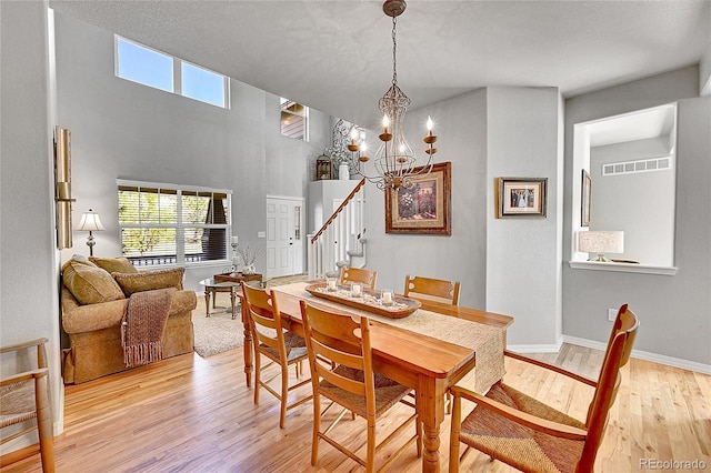 dining room featuring a chandelier, stairs, baseboards, light wood-type flooring, and visible vents