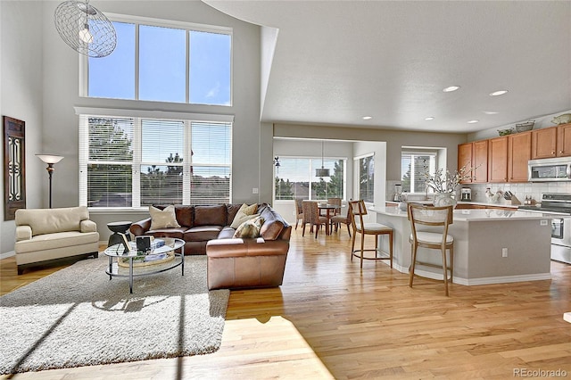 living area featuring plenty of natural light, recessed lighting, baseboards, and light wood-type flooring