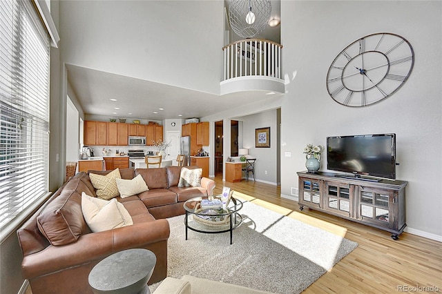 living room with plenty of natural light, a high ceiling, and light wood-style flooring