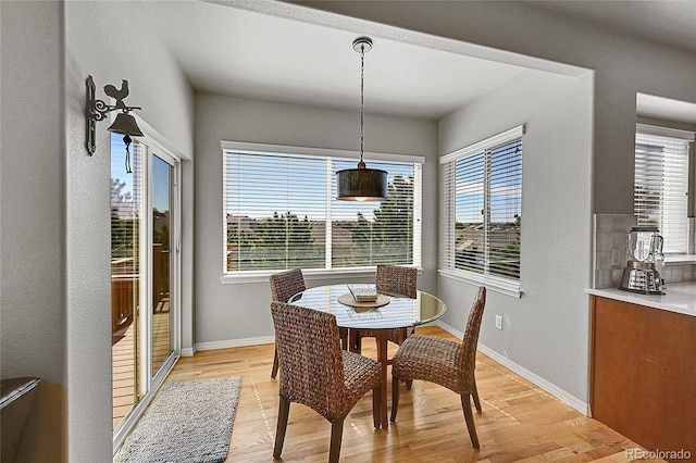 dining area featuring baseboards, a healthy amount of sunlight, and light wood-style flooring
