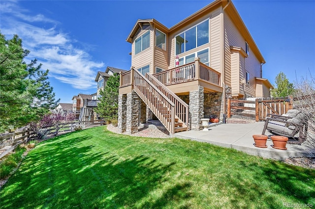 back of property featuring a lawn, fence, a patio, stairs, and stone siding