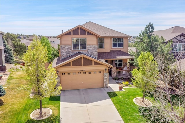 craftsman house featuring an attached garage, a front yard, stone siding, and concrete driveway